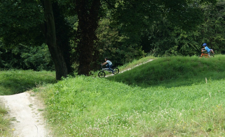 Two children on bikes riding on a BMX track.